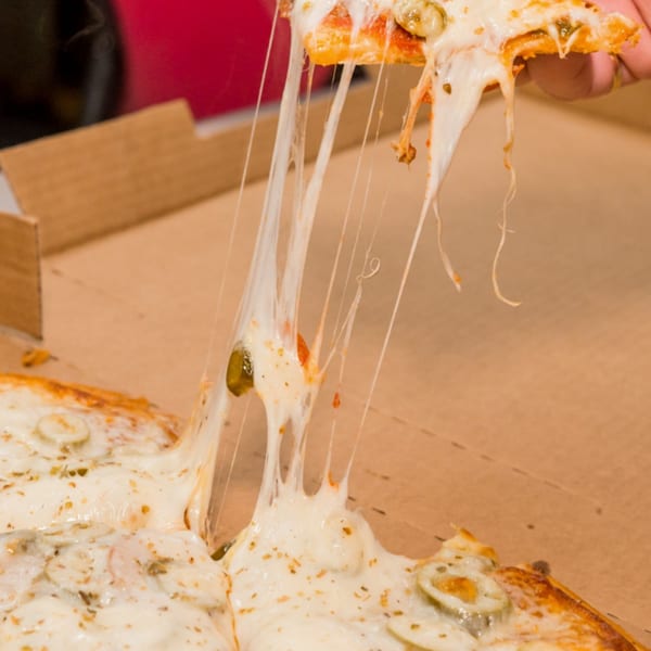 A hand lifts a slice of Bob's Tu Your Door Pizza, with long strings of melted cheese stretching.
