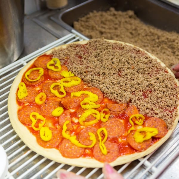 Uncooked Bob's Tu Your Door Pizza with pepperoni, banana peppers, and ground beef toppings.